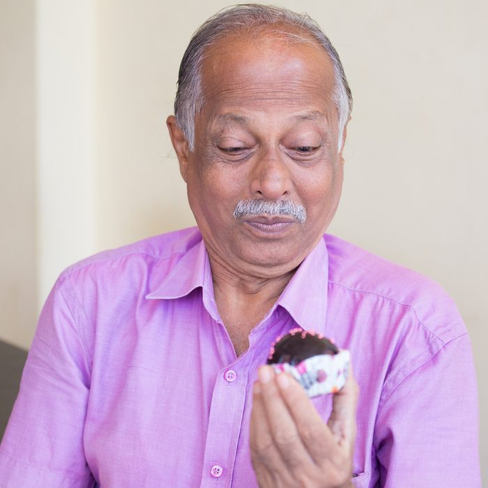 Closeup portrait of elderly gentleman in pink shirt craving dessert
