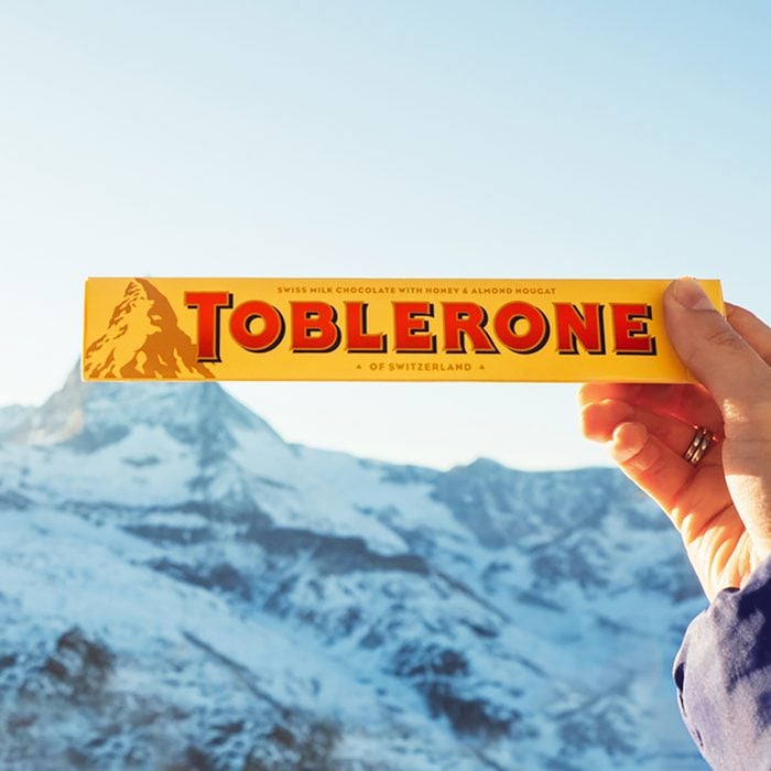 Female hand holds Toblerone chocolate on the Matterhorn mountain background in Switzerland. 