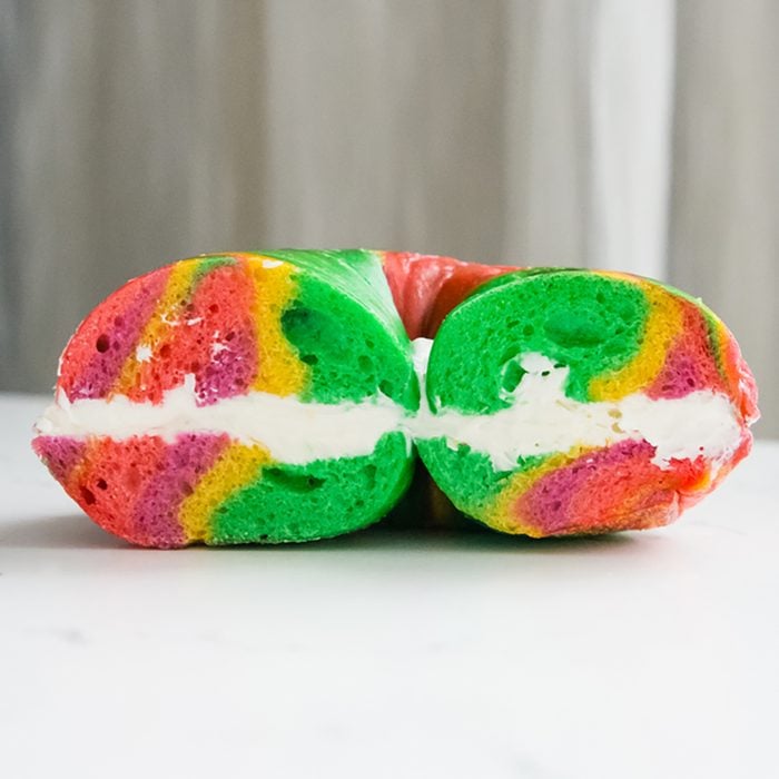 side photo of rainbow bagel with cream cheese;