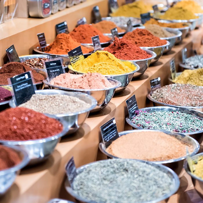 Many spices on display in bowls trays filled with herbs