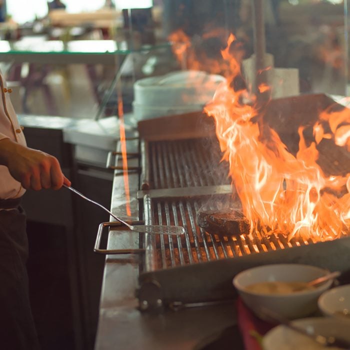 Master chef cooking delicious grilled meat steak with vegetables on a barbecue