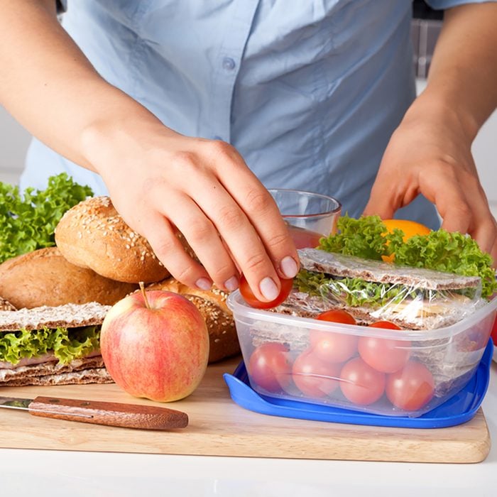 Woman in blue t-shirt preparing a lunchbox in the kitchen