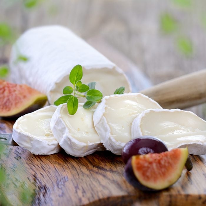 Goat cheese with figs and black olives on a wooden cutting board