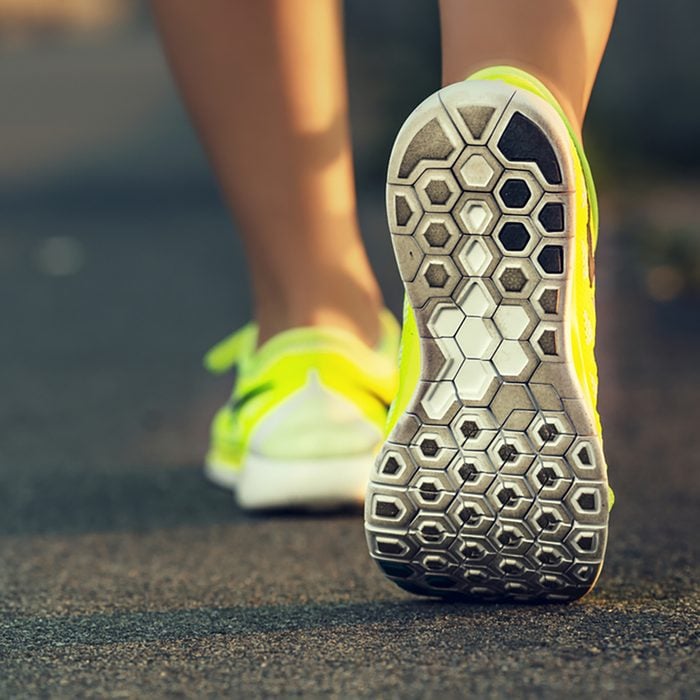 Runner woman feet running on road closeup on shoe.