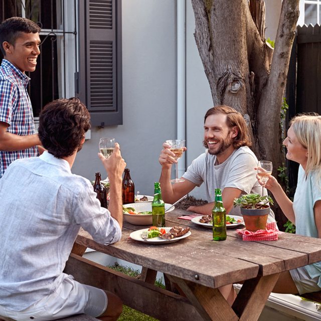man toasting speech at friends outdoor garden party with wine drinks