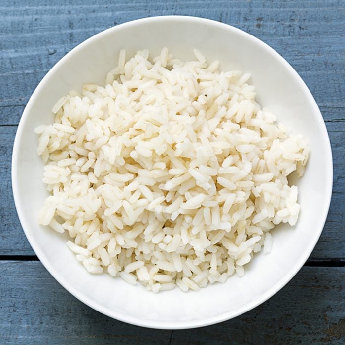 Boiled rice in a white china bowl on a rustic blue wooden table