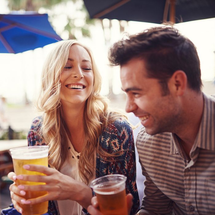 happy couple having a good time drinking beer together at outdoor pub or bar