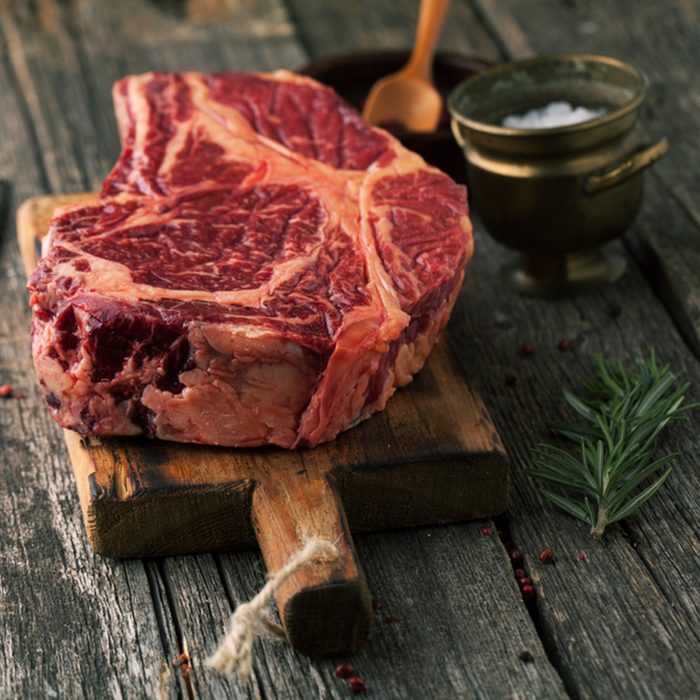 Raw fresh meat Ribeye Steak with pepper and salt on wooden background