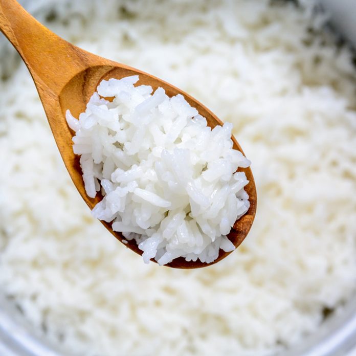 Cooked rice in pot with wood spoon