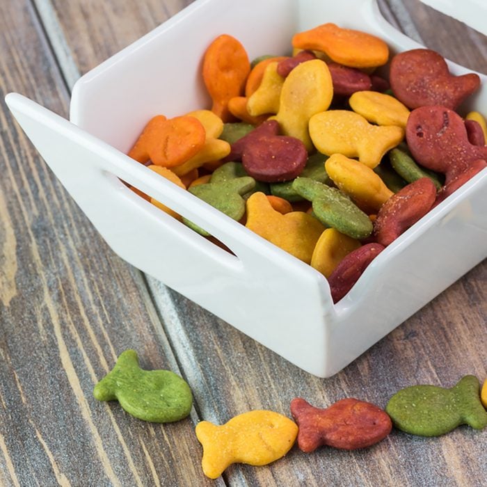 Close up of bowl with goldfish crackers on a wooden background.