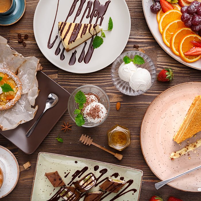 Different desserts with fruits and coffee, top view