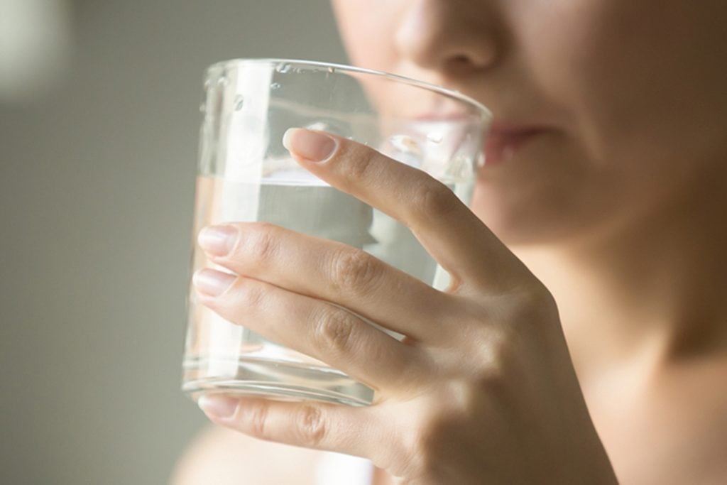 Female drinking from a glass of water.