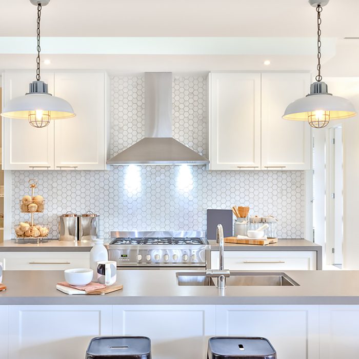 Luxury kitchen with the counter and stoves under lights near chimney