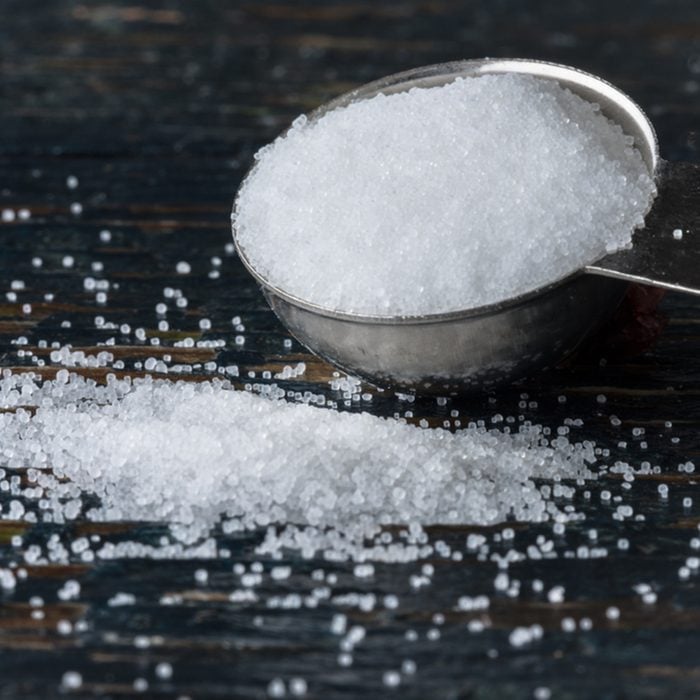 Table salt spilling from a measuring spoon