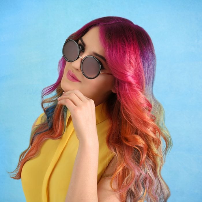 Young woman with colorful dyed hair on color background