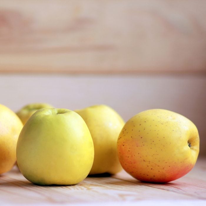 Yellow apples scattered on the wooden background.