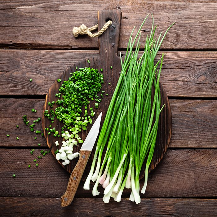 Green onion or scallion on wooden board, fresh spring chives