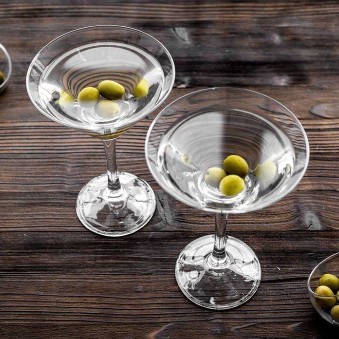 Martini cocktail in glass with olives at the bottom on dark wooden background top view.
