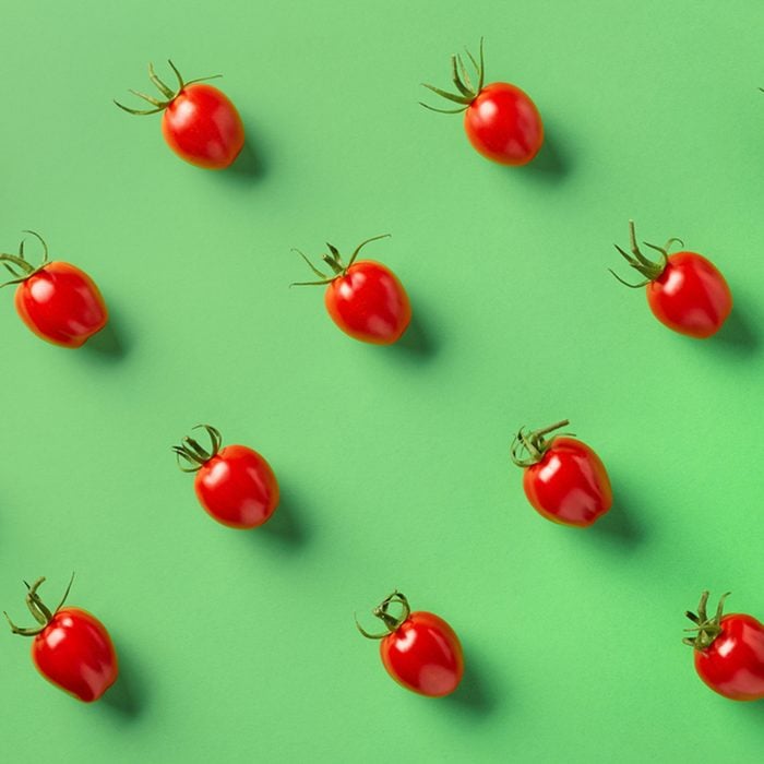 Colorful pattern of red tomatos on green background.