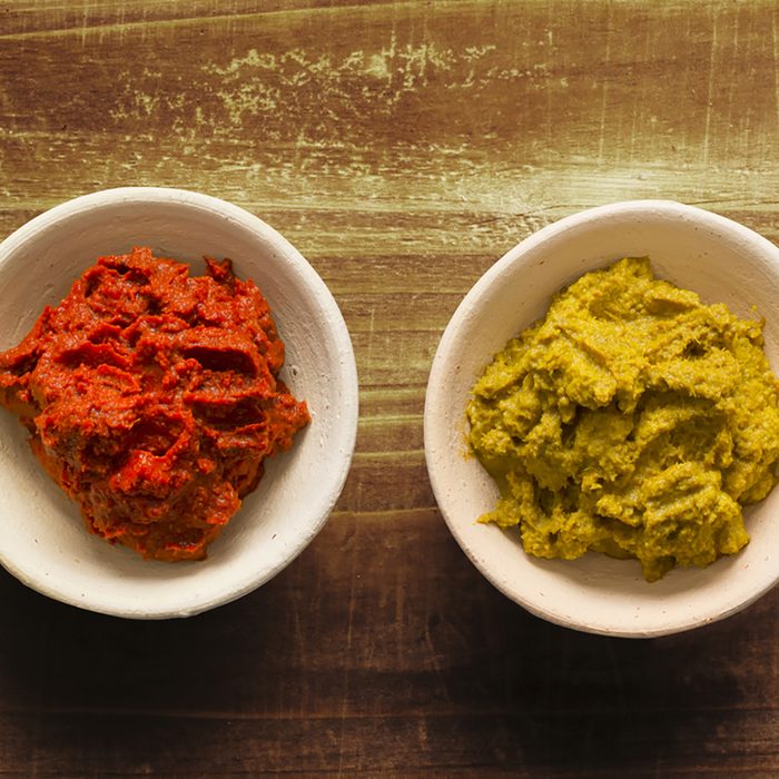 close up of bowls of rustic red and yellow indian curry paste