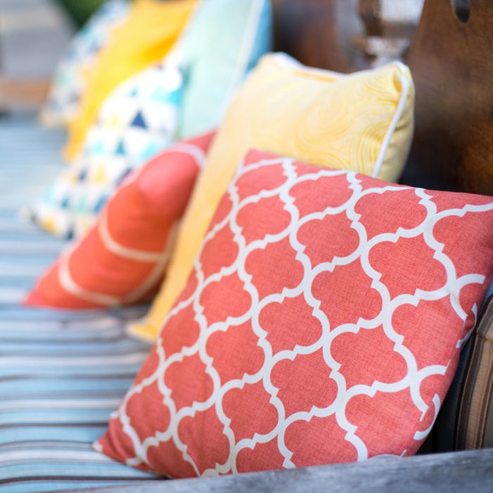 Close up on orange and yellow pattern throw pillows on an outdoor patio chair