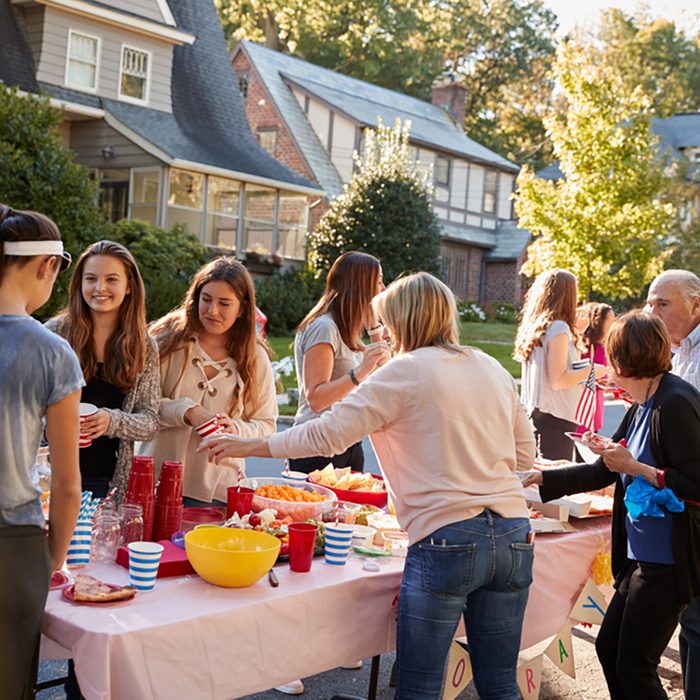 Neighbours talk standing around a table at a block party