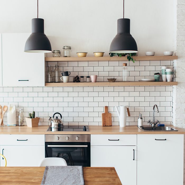 Modern new light interior of kitchen with white furniture and dining table