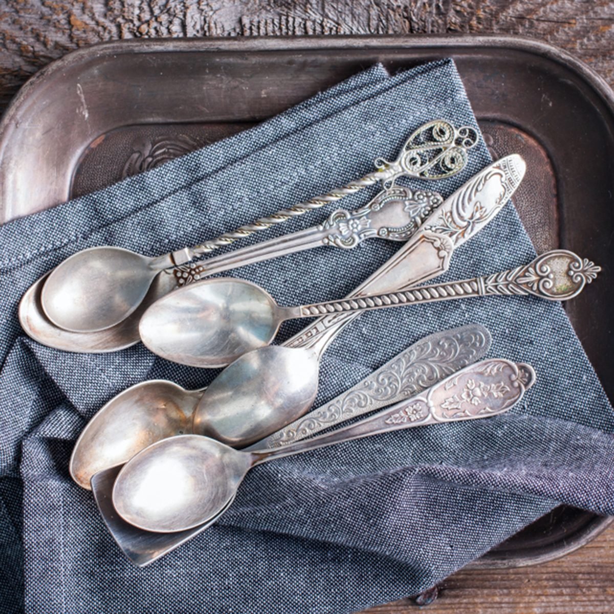 Vintage silver spoons on a tarnished silver tray with retro processing
