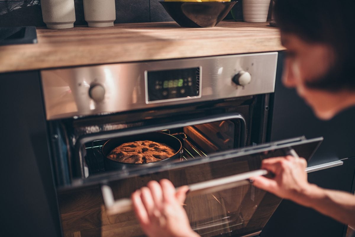 Woman standing by the oven and checking apple pie