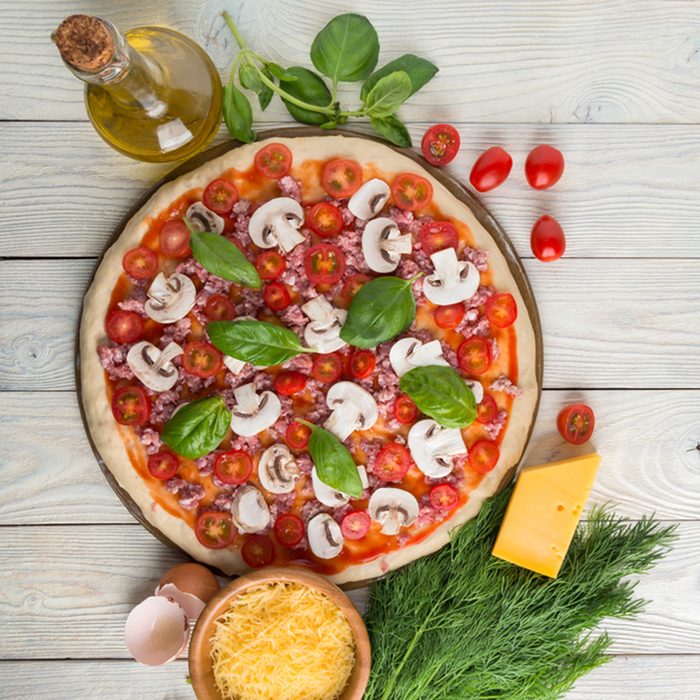 pizza on the stone for baking pizza and ingredients of pizza on a wooden background top view