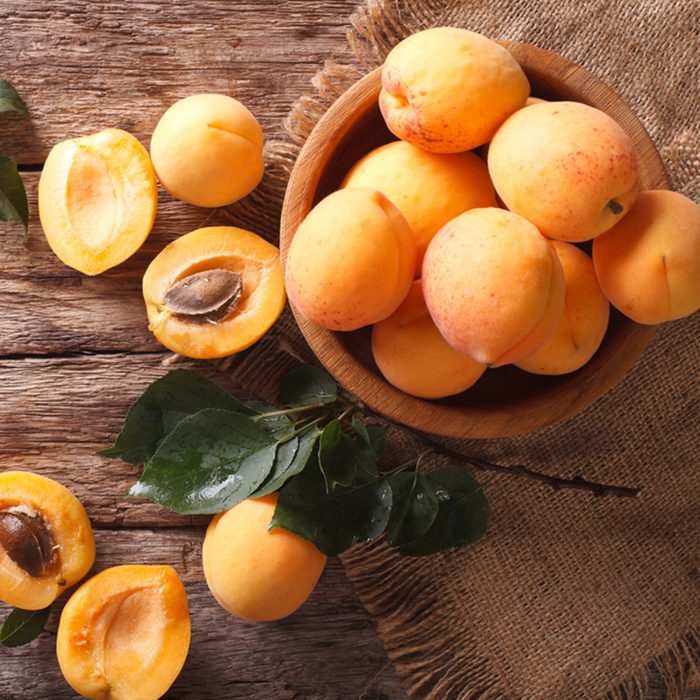 Delicious ripe apricots in a wooden bowl on the table close-up.