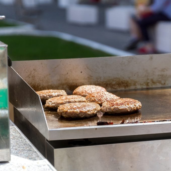 hamburgers and hotdogs cooking on grill outdoors