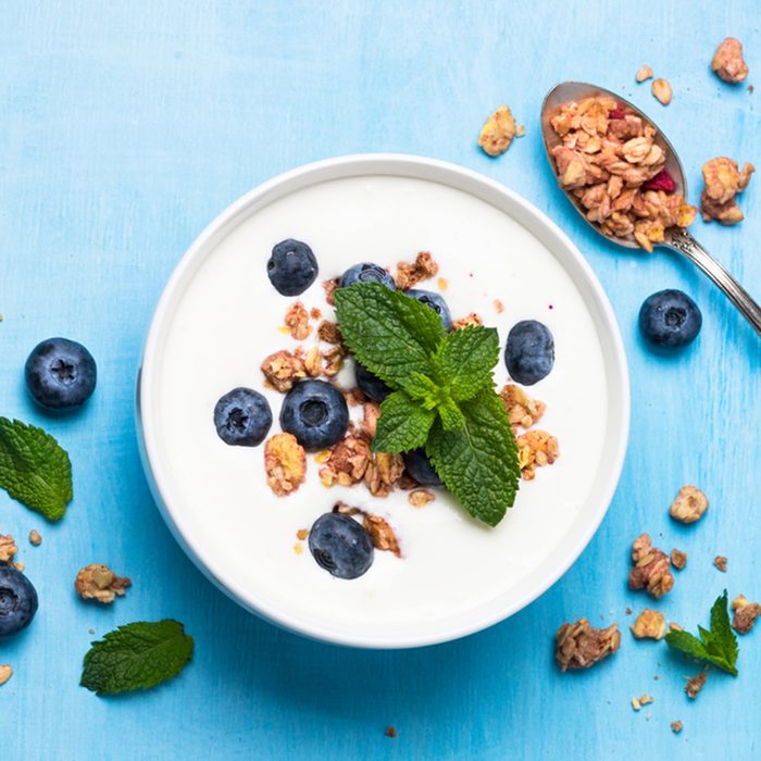 Greek yogurt granola and blueberries on blue table top view.