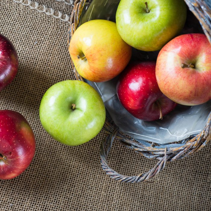 Apples in a basket on burlap and wooden background