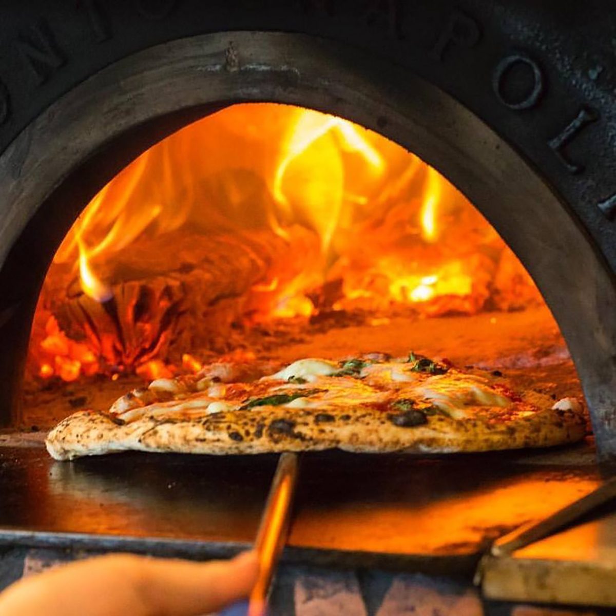a Settebello pizza going into a wood burning oven