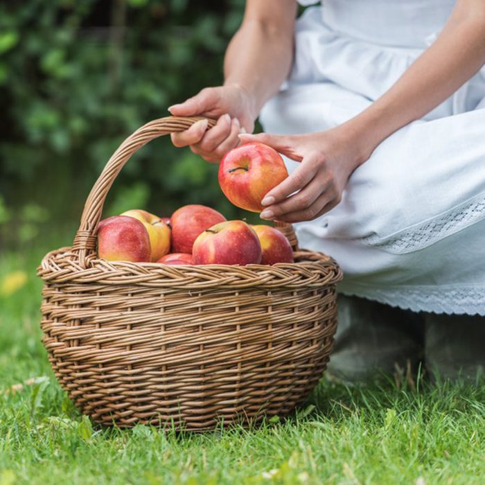 Child leaning down to put an apple in a basket