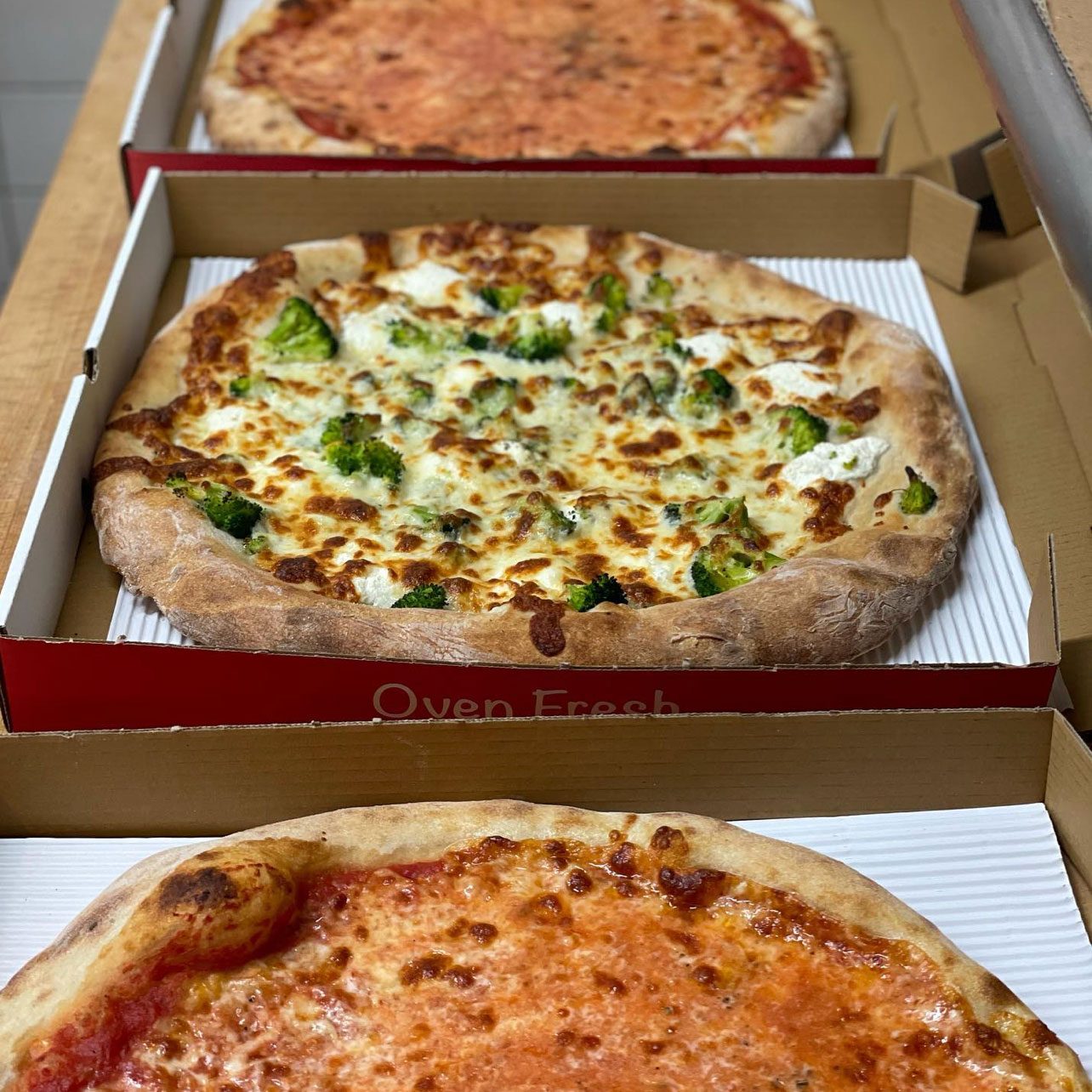 three pizzas in pizza boxes from the reservoir tavern in new jersey