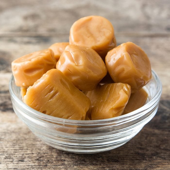 Toffee caramel candies in a crystal bowl on wooden table