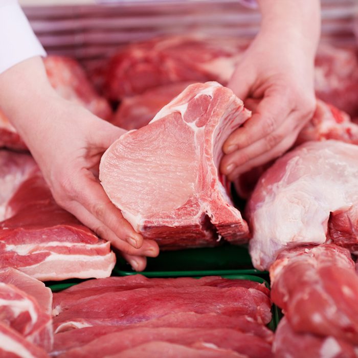 Closeup of butcher's hands holding meat piece in shop