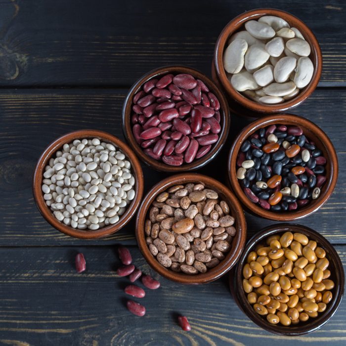 Assortment of beans on black wooden background.
