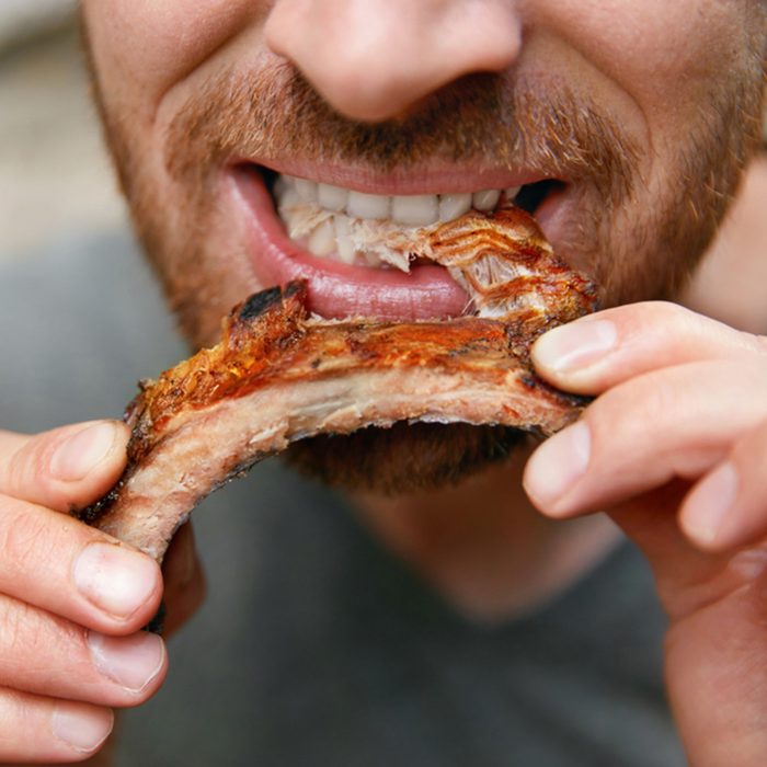 Man Eating Barbecue Ribs In Grill Bar Closeup.