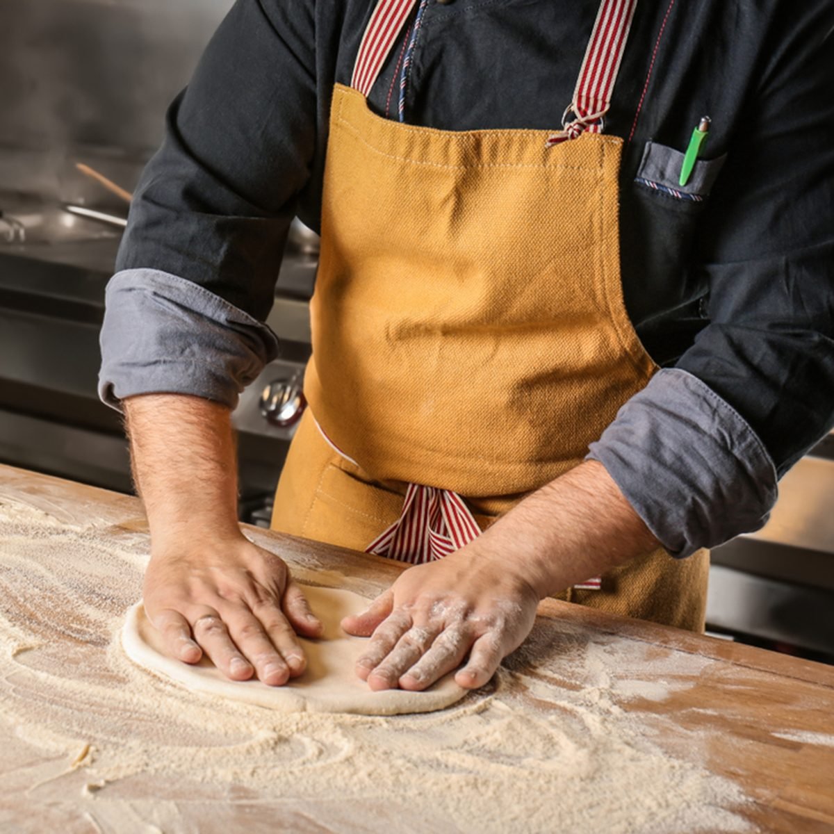Male chef preparing dough for pizza in restaurant kitchen