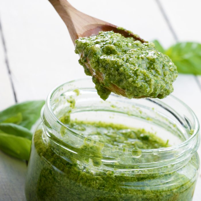 Glass jar of pesto sauce with wooden spoon