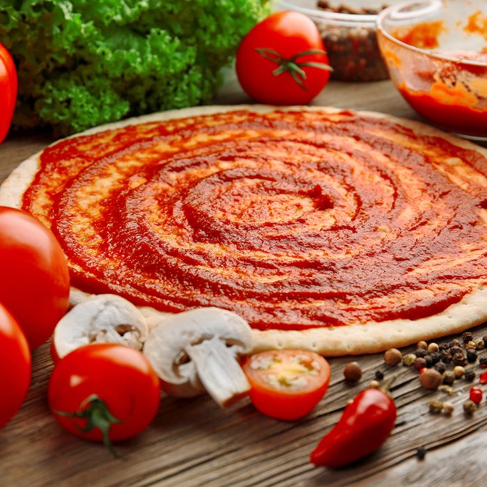 Dough basis with ketchup and ingredients for pizza