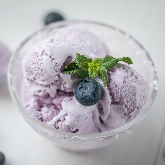 Blueberry ice cream in a glass bowl on white wooden table with ice cream spoon and berries. Shallow depth of field. Top view. ; Shutterstock ID 1113112034; Job (TFH, TOH, RD, BNB, CWM, CM): Taste of Home