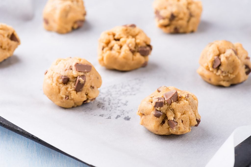 Raw cookie dough on a baking tray with parchment paper