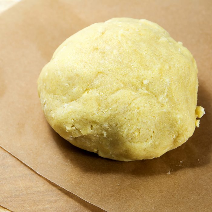 Fresh ball of raw shortcrust dough on baking paper, ready to roll it out, selected focus, narrow depth of field