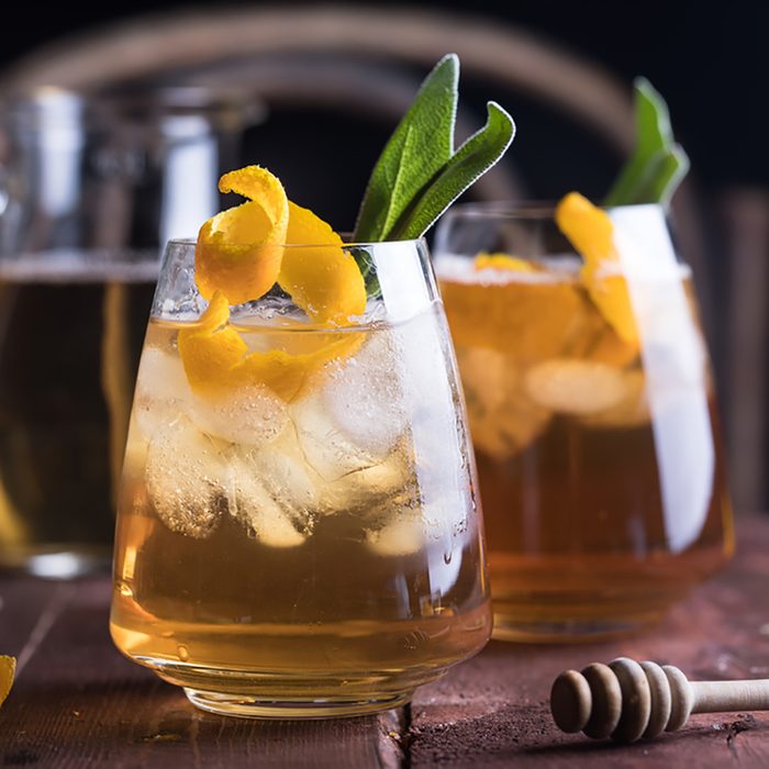 Refreshing iced tea with whiskey, honey, citron and sage on rustic wooden background