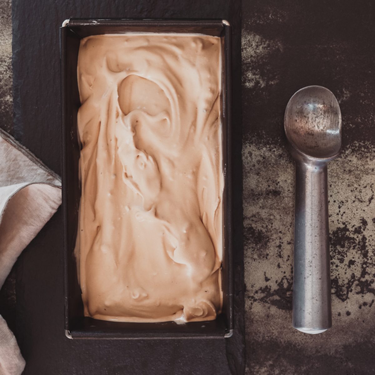 Homemade ice cream in frozen metallic tray on rustic surface. Top view, dark toned image, blank space; Shutterstock ID 569620816; Job (TFH, TOH, RD, BNB, CWM, CM): Taste of Home