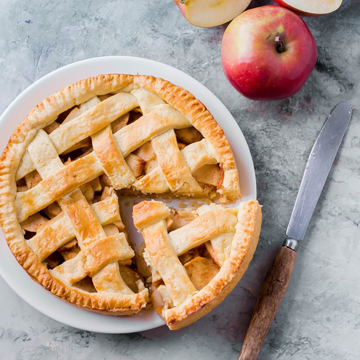 Popular American apple pie piece and cup of tea on gray table background. 